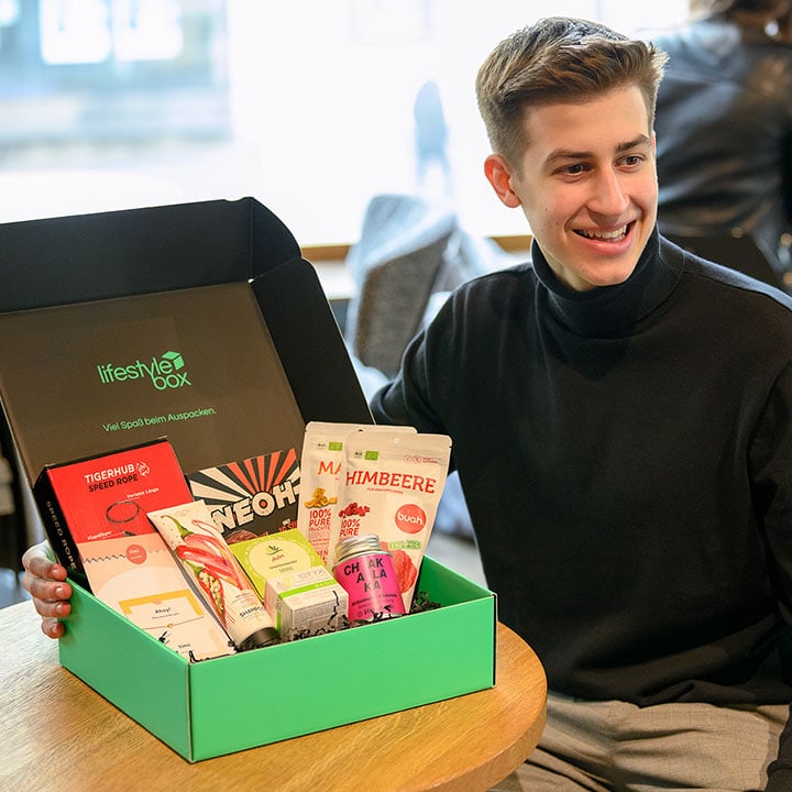 Moritz Lechner sitzt an einem Tisch mit der Lifestylebox darauf.